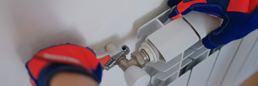 Close up,Of,Male,Plumber,Installing,Heating,Radiator,Using,Pipe,Wrench.